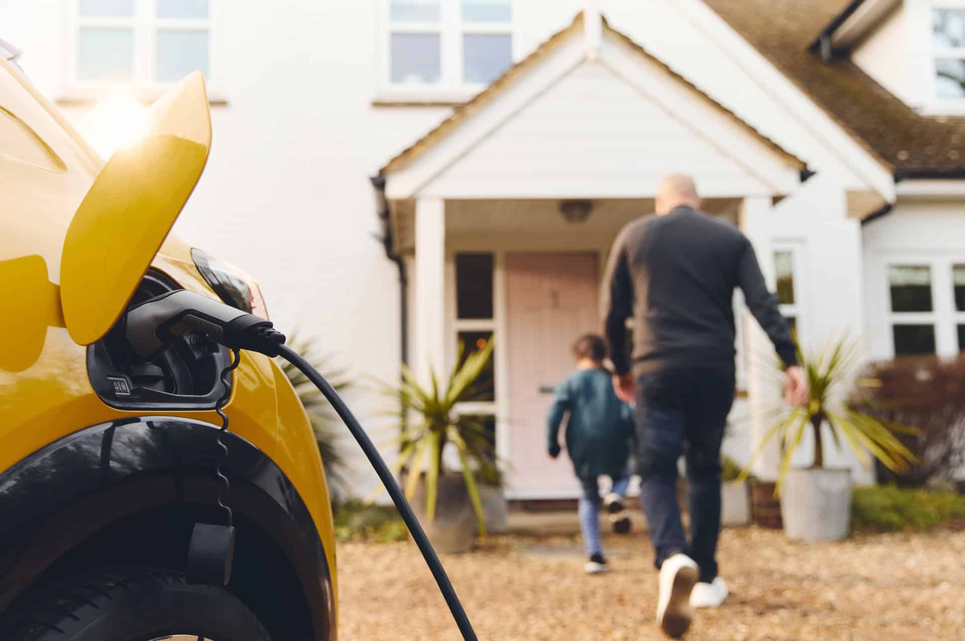 Electric car charging on driveway outside home with family